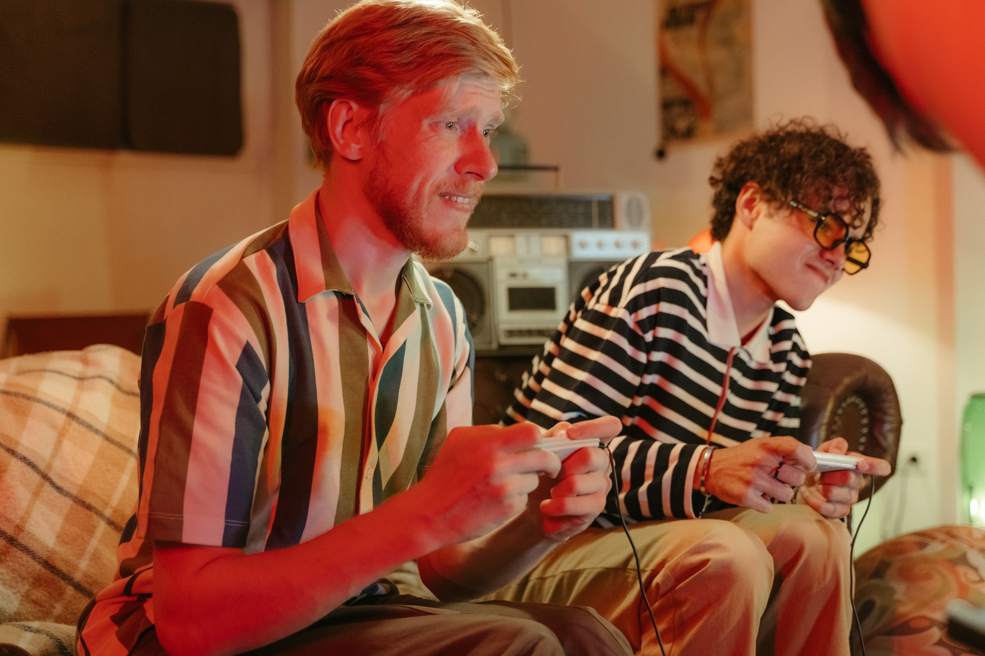 Two young men sitting on a couch playing a retro video game together